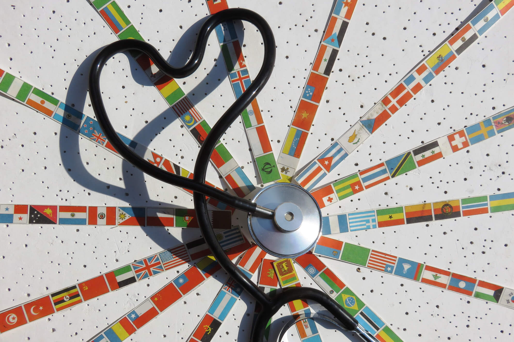 stethoscope in the middle of flags from around the world