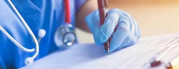 medical professional using a pen to write on paper