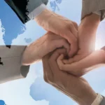 multiple hands joined together over the globe
