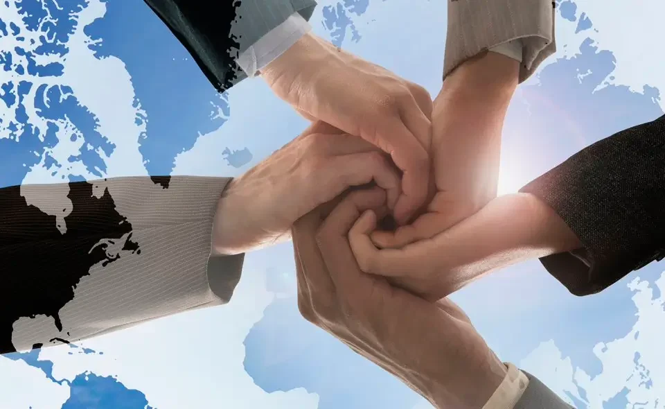 multiple hands joined together over the globe